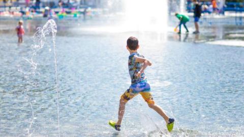 A stock photo of a child playing by a water feature.