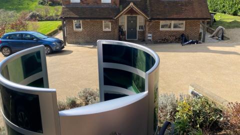 A picture of a solar arc sculpture in front of a house