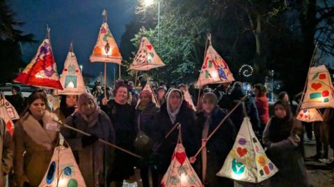 A group of people in a park carrying colourful lanterns as part of Bradford's First Festival of the Dead