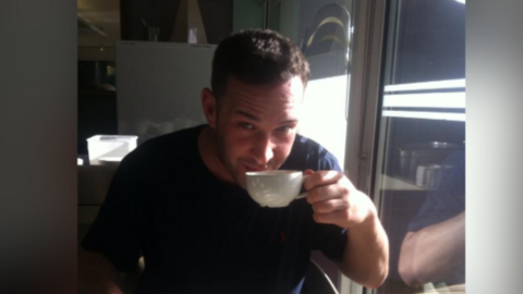 Ryan Kelly sipping a cup of tea with a plate in front of him.