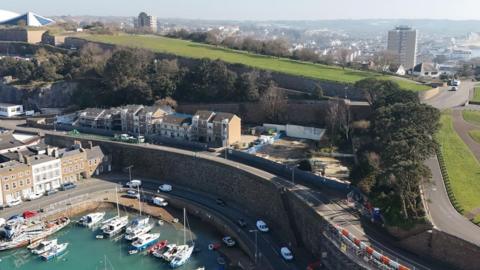 Overhead shot of the Haut du Mont site in St Helier, Jersey. A harbour with several boats moored up is next to the site where an explosion in December 2022 killed 10 people.