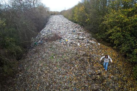 An aerial photograph shows environmental campaigners filming content for social media on a large pile of fly-tipped waste, dumped in a field between the River Cherwell and the A34 near Kidlington, Oxfordshire, west of London on November 16, 2025.