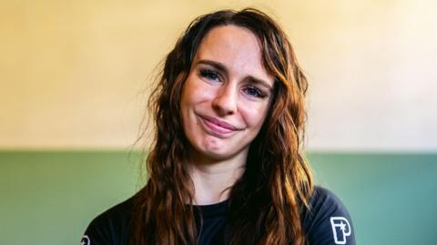 Ffion Davies smiling wearing a black, MMA-branded t shirt.