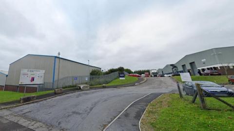 A view of part of the industrial estate showing warehouses, roads and parked cars. 