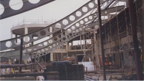 An image from the exhibition of Rugby Art Gallery and Museum under construction. Concrete, scaffolding and steel beams have been put into place with building supplies around the site. 