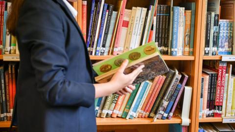 A child flicking through a book in a library. 
