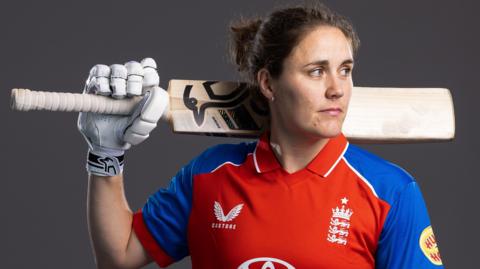 Nat Sciver-Brunt looks to the side while holding a bat in a photo shoot