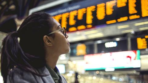 A woman looks at the train timetable at a station