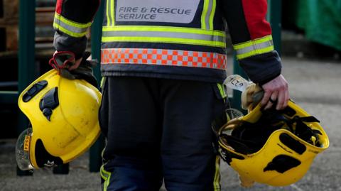 File image of a fire officer holding helmets