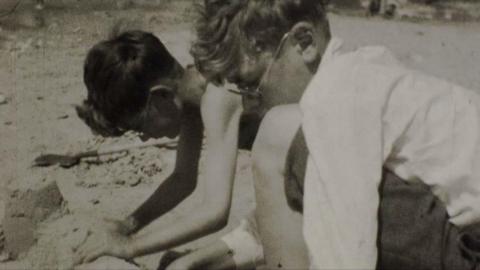 A black and white video of two children building a sand castle