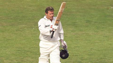 Robin Smith of Hampshire raising his cricket bat in the air and holding his helmet