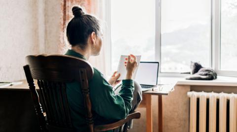 A woman from the back sitting in front of a laptop