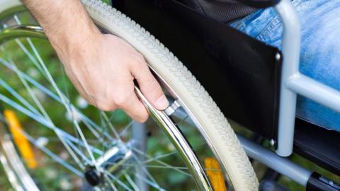 A man with his hand on the wheel of a wheelchair