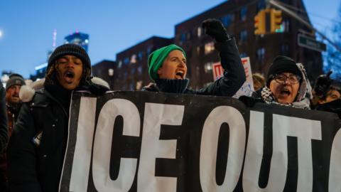 People in New York City carry a banner that reads "ICE OUT".