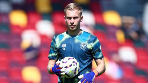 Matthew Cox holds the ball and prepares to restart play during a match