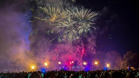 Multi-coloured fireworks light up the skies at Downend at the event organised by the local Round Table. Rockets are exploding in the sky as a large crowd watches from below