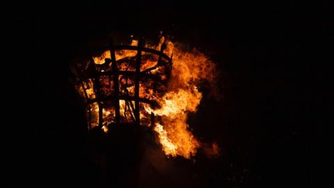 A beacon burns at night. 
