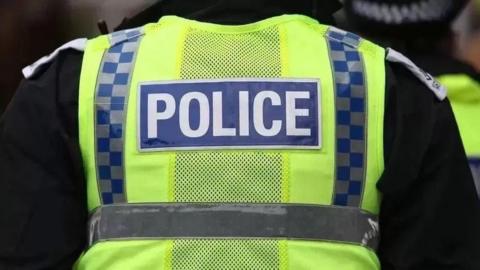 A police officer with their back turned in a hi-vis vest