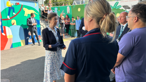 Princess Anne talking to hospital staff in a colourful courtyard 