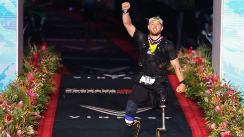 Billy Monger with his fist in the air, celebrating a new Ironman world record