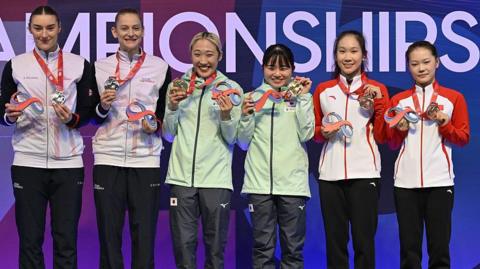 Japanese gymnasts Hikaru Mori and Saki Tanaka, British gymnasts Isabelle Songhurst and Bryony Page and Chinese gymnasts Xinxin Zhanf and Yicheng Hu on the podium