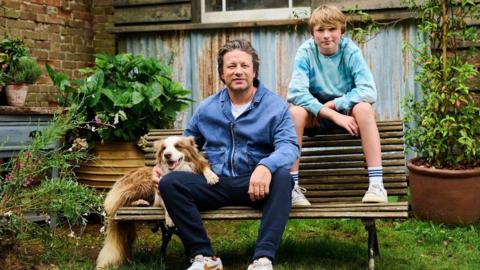 Jamie Oliver, his son Buddy and their dog sat on a bench