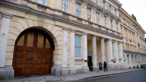 The exterior of Bristol Crown Court. It is a grand stone building, with columns at the entrance and a large arched vehicle entrance. 