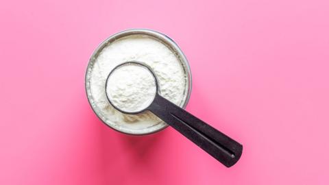 Tub of creatine with a measuring spoon in it which is also filled with creatine