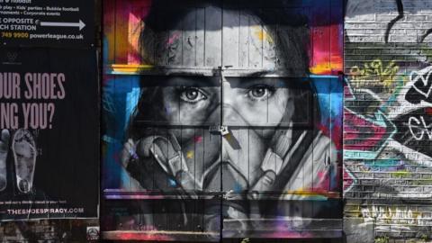 French street artist Zabou painted artist BK Foxx wearing her graffiti mask on a wall in East London