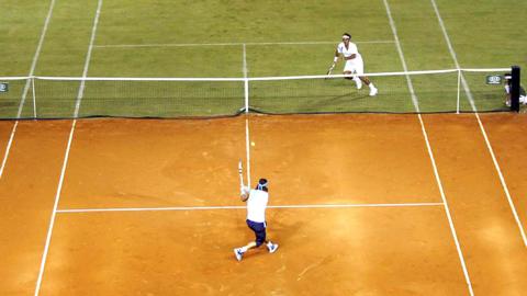 Rafael Nadal takes on Roger Federer on a tennis court made of half grass and half clay