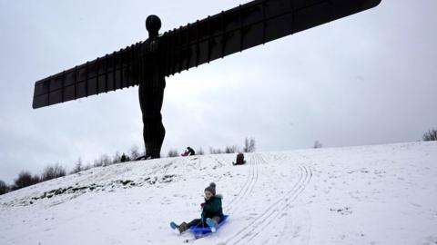 Boy sledging next to Angel of the North