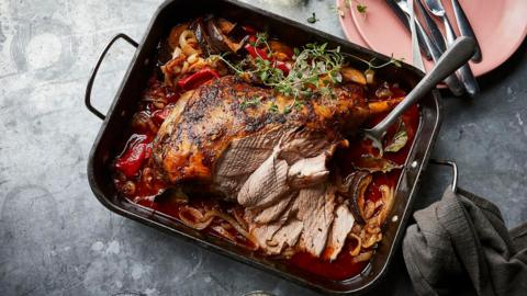 A roasting tin filled with ratatouille and a slow-roast leg of lamb