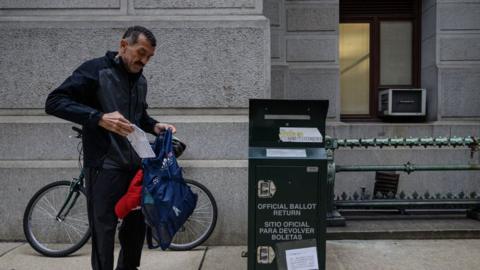 Man casting ballot at mail drop box