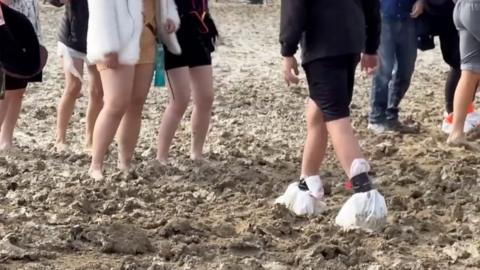 Revellers walk through mud