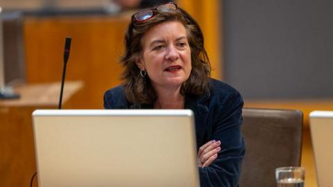 Eluned Morgan sitting with arms folded in the Senedd chamber