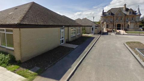 A Google Street View of Dorchester Learning Centre, a single-storey yellow brick building. In the distance is a historic looking house.