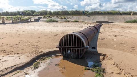 Overflow pipe outlet at the high tide level on an English coastal sand beach in Yorkshire