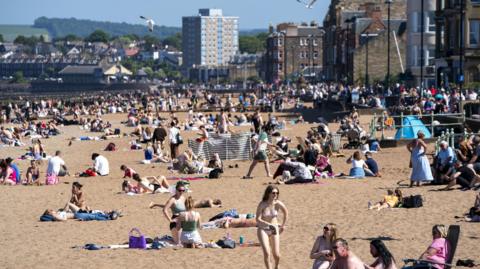 Portobello beach on a hot day with lots of people sunbathing.