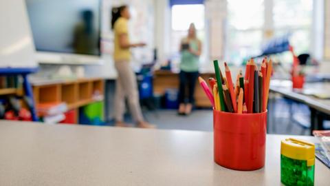 A school classroom with a box of pencils in the foreground