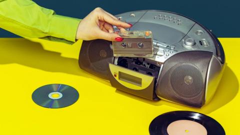 A hand putting a tape into a tape and CD player