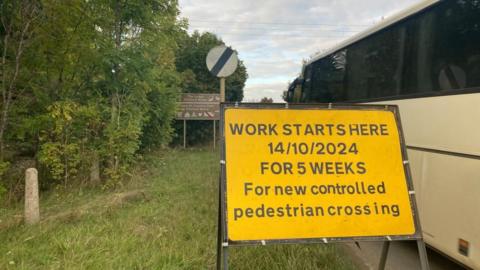 Road sign for roadwork and coach driving past