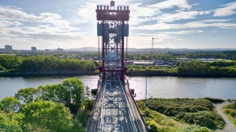 The Newport Bridge spanning the River Tees. Trees line either side of the water.