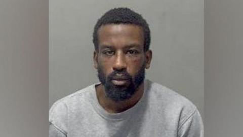 Nathaniel Sereaton: a man with black hair and a black beard wearing a grey, round-necked T-shirt

