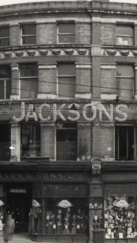 A black and white photo of the front of a department store with the word Jacksons.