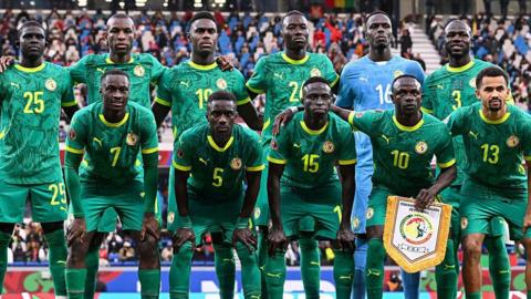 Senegal players wearing green shirts, shorts and socks pose for a team photo