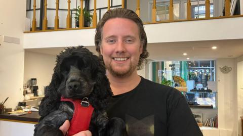 Matt Porter, owner of Porter Hill Tea Company, smiling in his tea shop with a dog