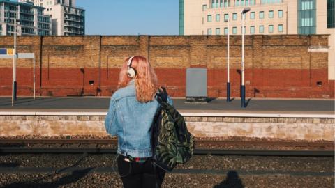 A woman waits at a train platform