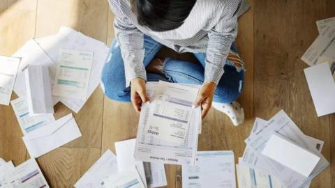 Person sitting on the floor looking at their tax invoices