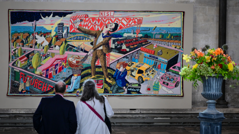 A man and woman observing a colourful tapestry