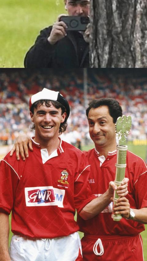 Two Swindon Town FC players stood in red T-shirts and holding cup